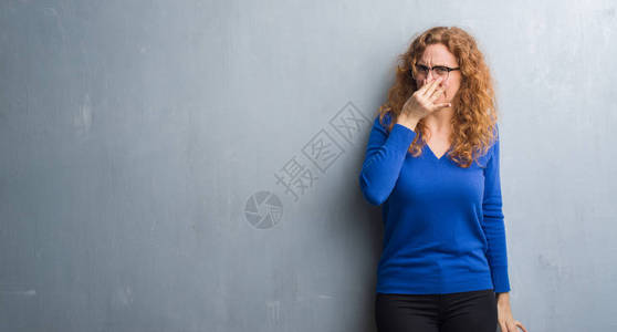 灰墙上的红发女青年闻到臭味恶心不可容忍的气味图片
