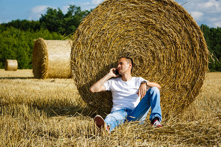 笑的男子使用智能手机坐在小麦图片