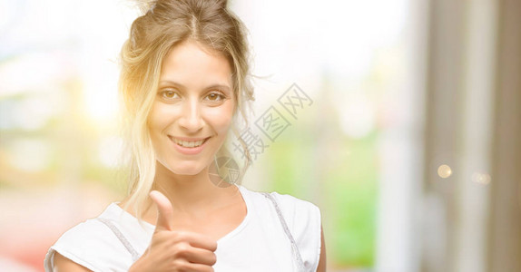 年轻美丽的女士笑着微笑向摄影机举起手势表达喜欢图片