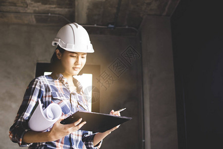 持有纸质检查的亚洲工程师女在建筑工地进图片