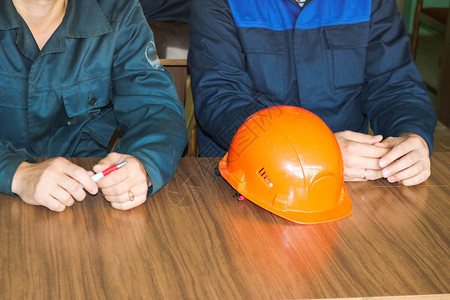 一个在桌子上戴着橙黄色头盔的工程师正在学习图片