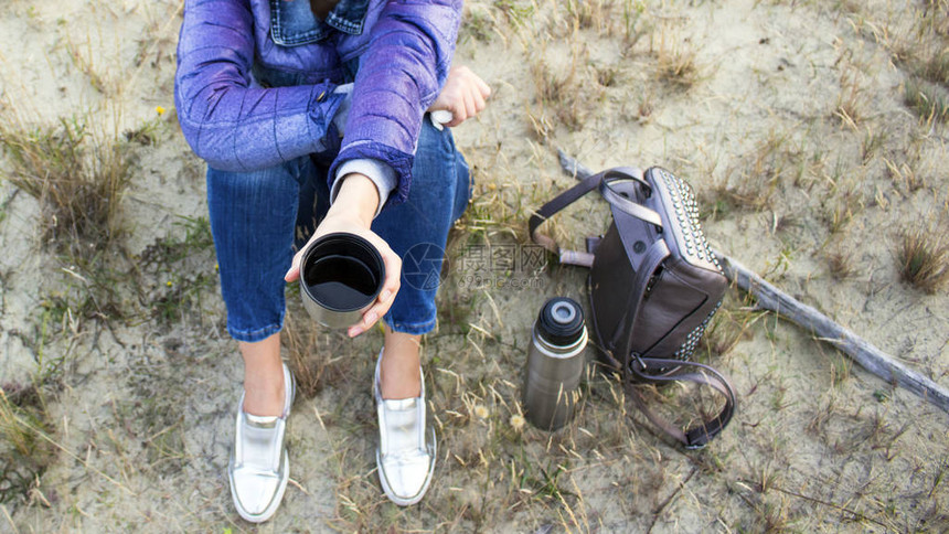带着热水瓶和背包的大自然女孩喝热茶图片