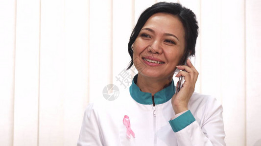 美丽快乐成熟的亚洲女医生在她的实验室外套上戴着粉红丝带癌症意识符号图片