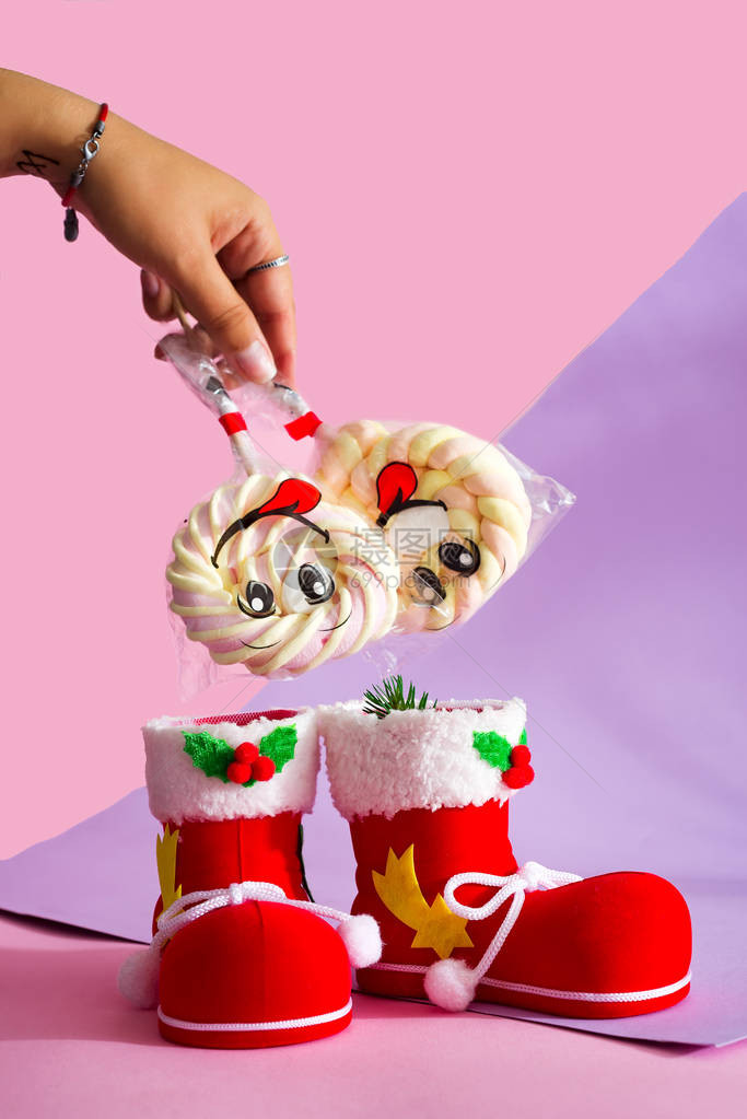 女手把圣诞老人靴子糖果棉花糖放在一根棍子上图片