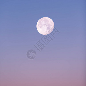 在柔和的粉红色和蓝色冬季天空中升起的近满月背景图片