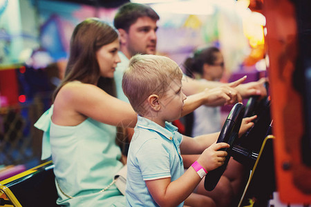 家庭母亲父亲和小男孩在游乐场的游戏机里图片