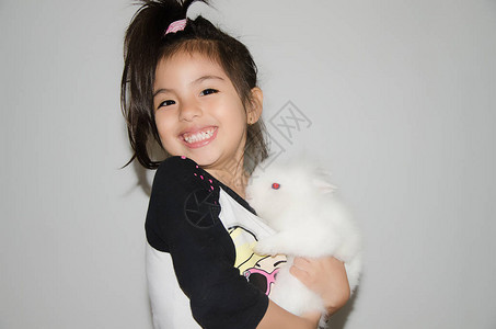 可爱的小女孩微笑与白兔笑孤立图片