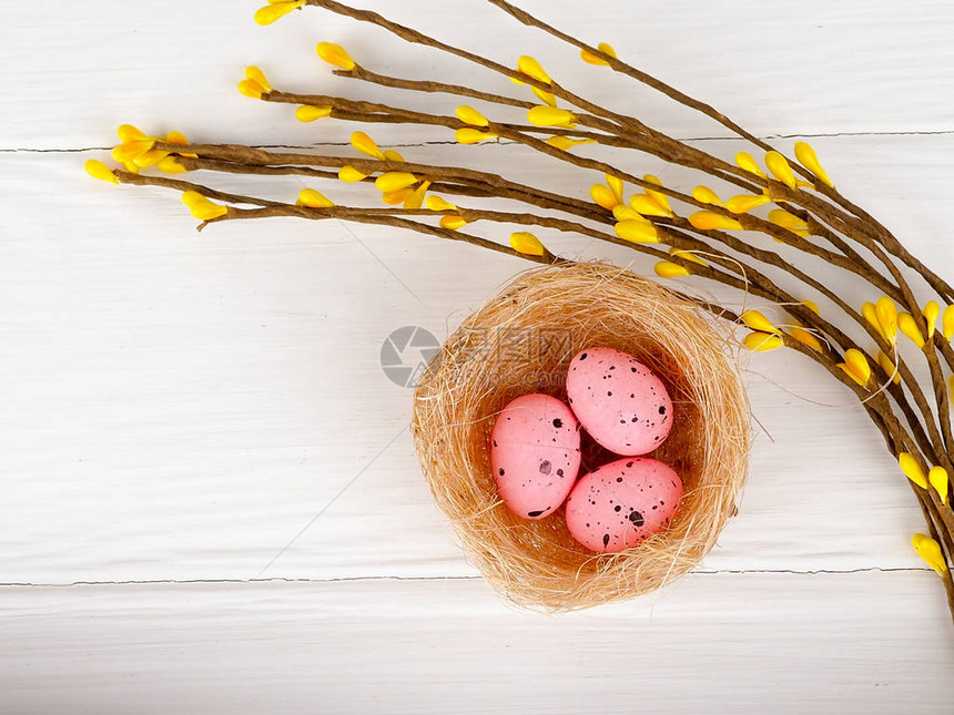 粉色复活节鸡蛋在白木本底的巢图片