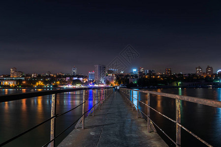 河上的旧长金属码头夜晚的城市景观图片