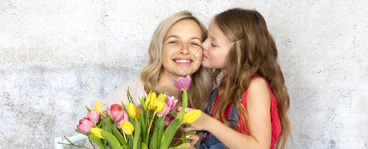 女儿亲吻并用五颜六色的鲜花祝贺母亲图片