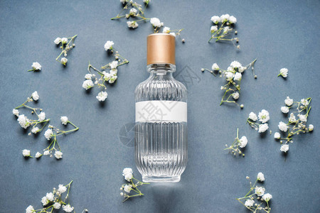 透明的香水瓶子灰色背景的美丽鲜花图片