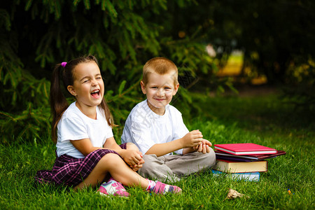 两个孩子坐在公园的绿草上看书图片