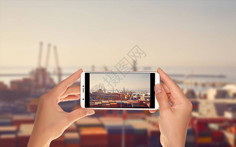 一位游客正在用手机拍下海港码头的照片图片