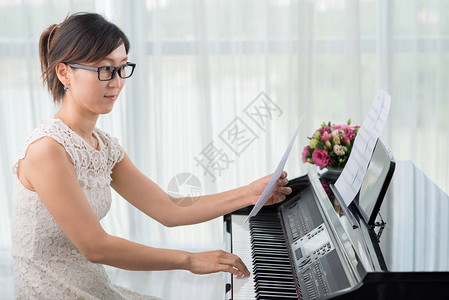 富有创意的亚洲年轻女在坐钢琴图片