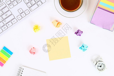 咖啡杯和键盘旁边的白色桌面上的彩色便签贴纸顶视图片