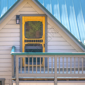 带黄色门和灯的阁楼阳台通过阁楼进入的房子的小阳台房子有一个蓝色的屋顶图片