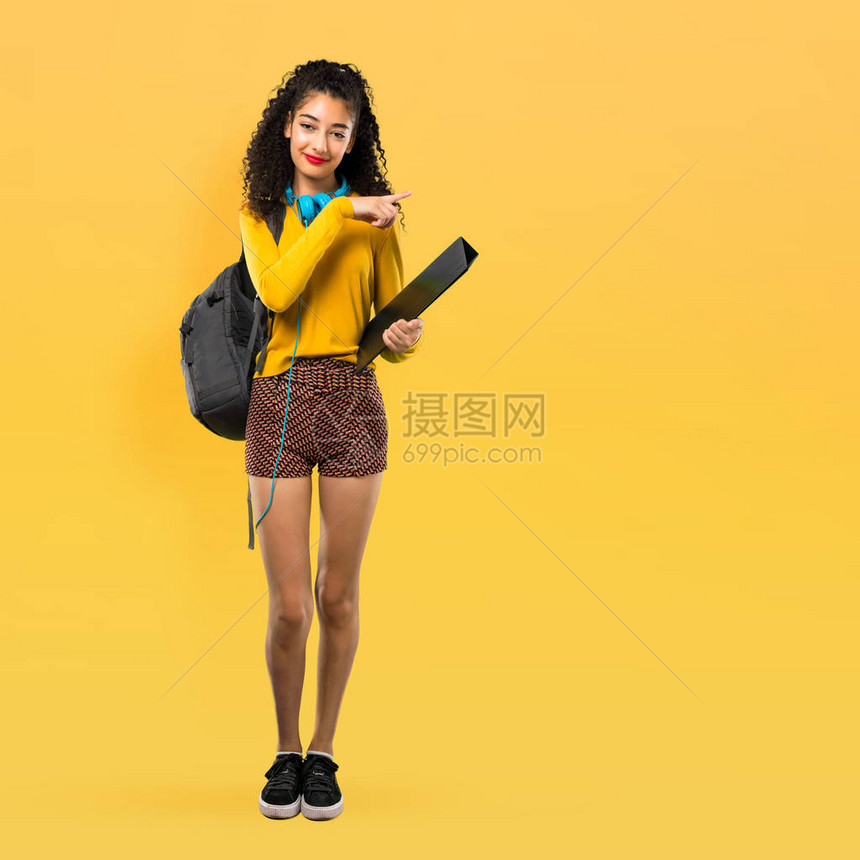 全身卷发的少女学生手指向侧面在黄色背图片