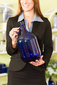 拿着闭合的大蓝色瓶子的微笑的女实业家背景图片