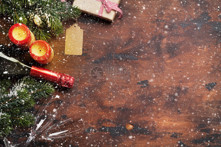 圣诞礼物盒蜡烛香槟和木本上雪所覆盖的fir树枝顶端视图xma背景图片
