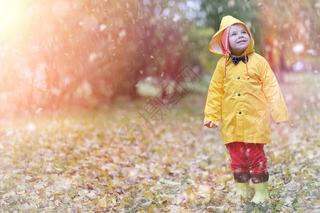 一个穿着雨衣的孩子在秋日户外散步图片