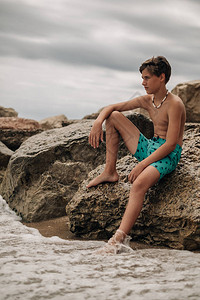 男孩坐在岩石上思考而波图片