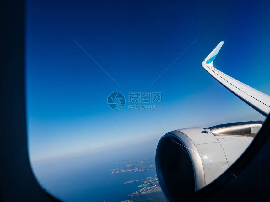 在阳光下从高空飞行的飞机涡轮机窗口欣赏云景图片