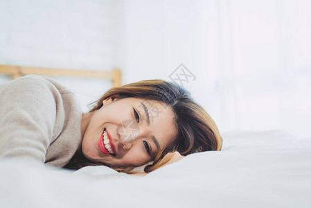 肖像美丽的年轻亚洲女人早上在家的床上图片