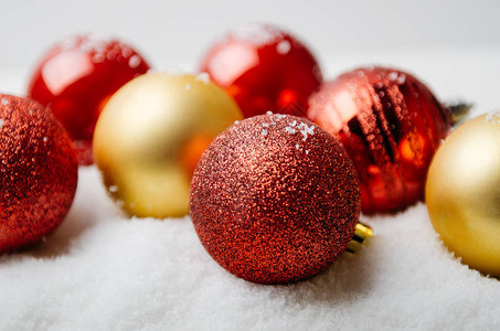 白色背景上人造雪上的红色和金色圣诞球图片