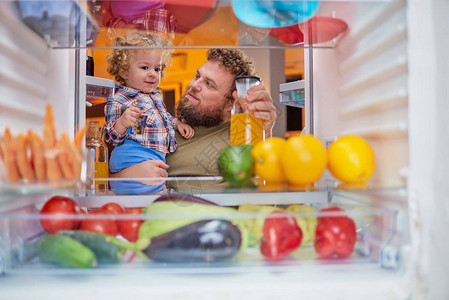 父亲和儿子深夜从冰箱里取食物图片