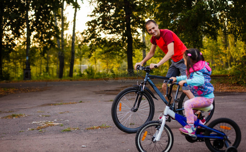 快乐的年轻父亲和他的小女儿在绿公园骑自图片