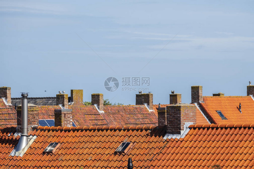 屋顶上用橙色屋顶瓷砖在旧邻居的蓝天对着蓝图片