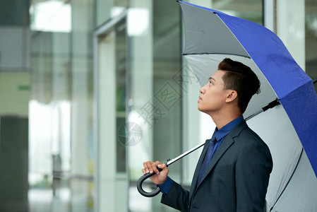 亚洲商人在雨天气下带蓝伞屋外的亚洲商人图片