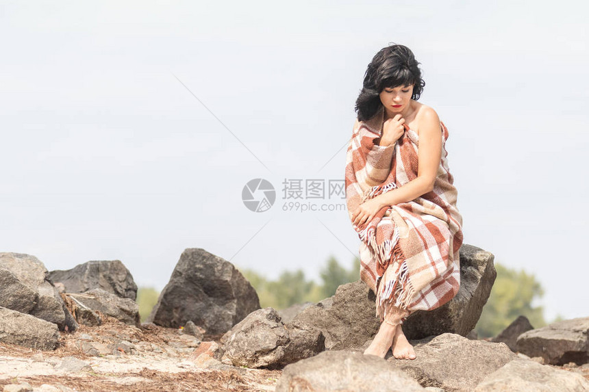 可爱快乐美丽感的黑发女孩坐在河边的石头上休息图片