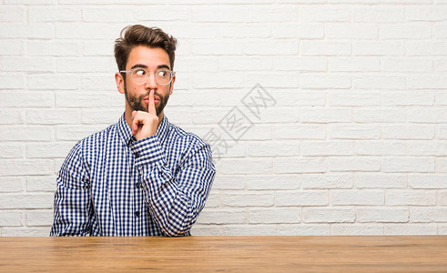 年轻的天主教男子坐着保守秘密或要求沉默严肃的面背景图片