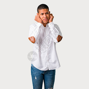 年轻的非洲美国人双手耳用手遮住双耳在灰色背景上令图片