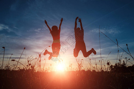 快乐的年轻夫妇在美丽的夕阳下跳跃自由幸福快乐的概念希望图片