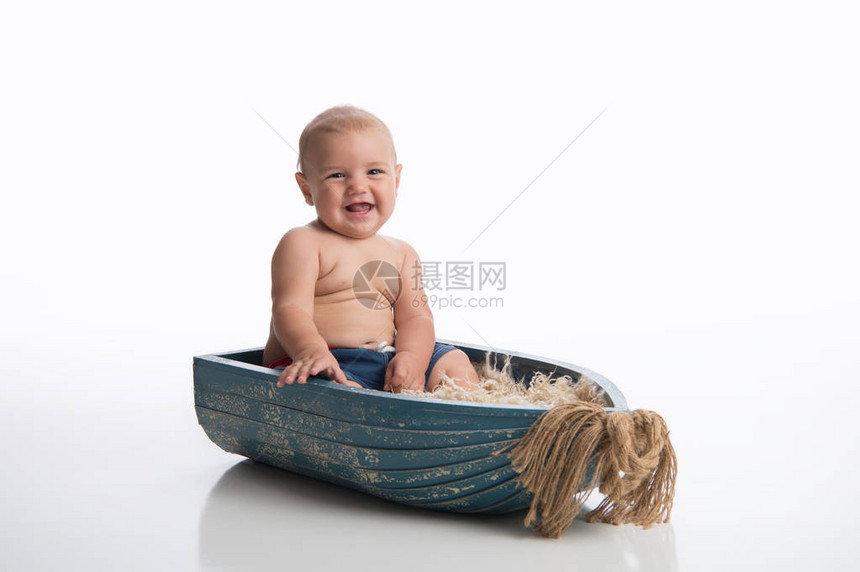 一个笑着七个月大的男孩坐在一个生锈的木碗里图片
