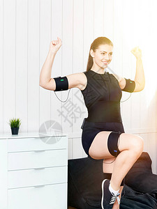 美丽的年轻女孩在机器上锻炼肌肉刺激运动健身的创新技术电动肌肉机图片