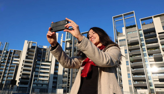 黑发女人在建筑物户外使用手机和自拍照片图片