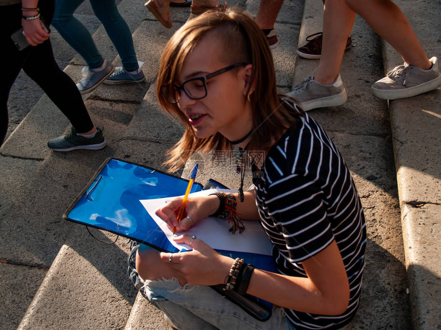 一名十几岁的女子在大学校园的楼梯上坐在一个文件夹图片