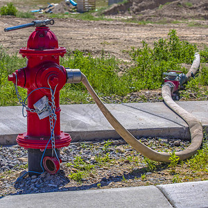 与软管连接到出口的红色消防栓岩石地面上的红色消防栓软管连接到出水口背景