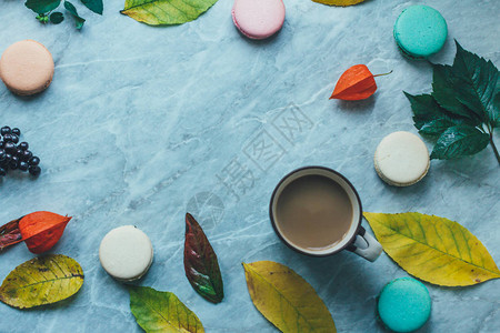 大理石表面的黄秋叶咖啡和法国面糊红玉饼图片