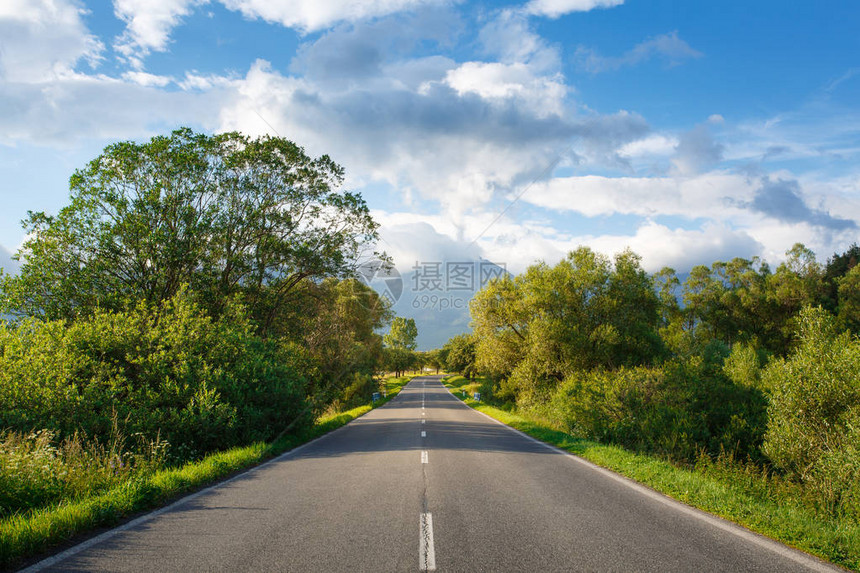 从山上的柏油路上的风景以山蓝天和云彩为背景高塔特拉山通往山区的道路两侧的图片