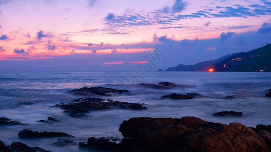 在日落风景背下以岩石绘制的戏剧天空和波浪海景图片