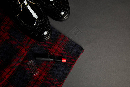 红条纹大衣黑牛福鞋和黑色背景的口红图片