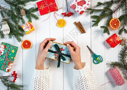 女人的手在桌子中央拿着一份手工制作的圣诞或新年礼物图片