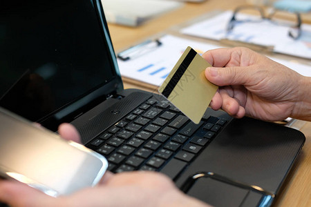 女人拿着信用卡使用智能手机进行网上购物图片