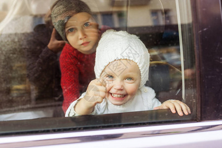小孩子们在车前做鬼脸小孩在夏日透过汽车玻璃看车图片