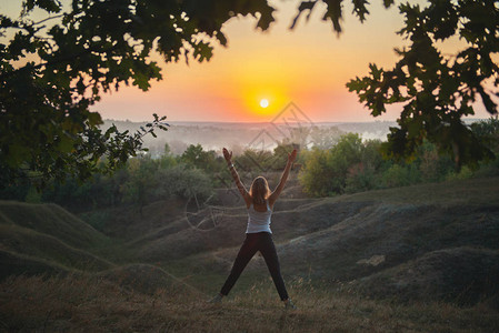日落时练习瑜伽的年轻女子图片