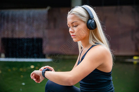 体育女跑选手在城市使用智能手表时用耳听器收图片